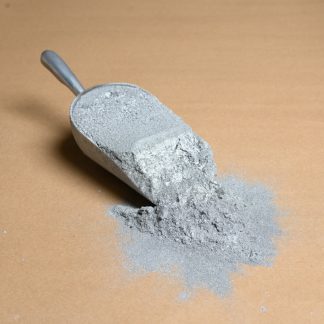 A spoon full of gray powder on a brown surface.