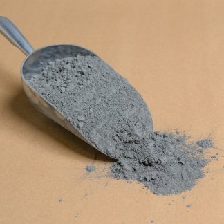 A scoop of gray powder on a brown table.