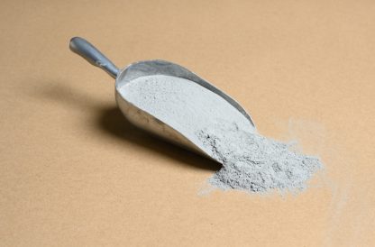 A scoop of gray powder on a beige background.