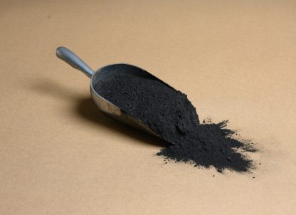 A scoop of black powder on a brown background.
