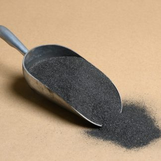 A scoop of black sand on a beige background.