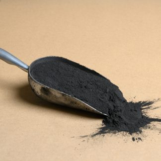 A scoop of black powder on a beige background.