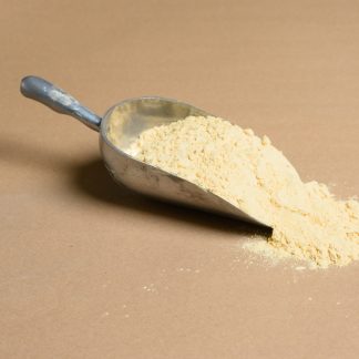 A scoop of yellow powder on a beige background.