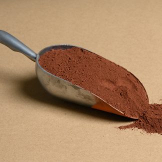 A scoop of cocoa powder on a brown background.