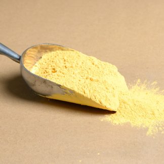 Yellow powder in a metal scoop on a beige background.