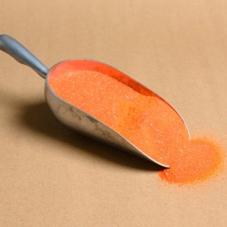 A scoop of orange sugar on a brown surface.