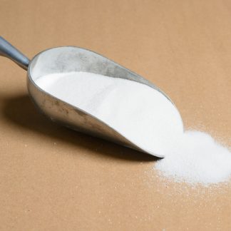 A scoop of sugar on a brown surface.