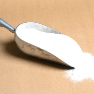 Potassium-Perchlorate powder in a scoop on a brown surface.