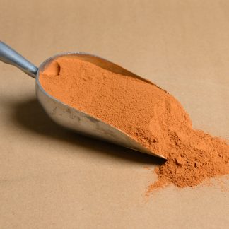 Orange powder in a metal scoop on a brown background.