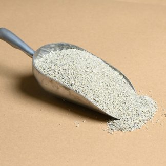 Sand in a metal scoop on a beige background.