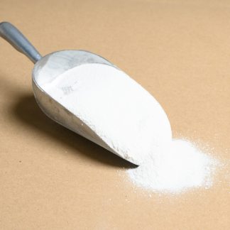 A scoop of Sodium-Benzoate white powder on a brown surface.