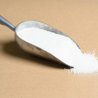 A scoop of white sugar on a beige background.