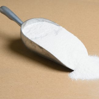 A scoop of Sodium-Salicylate white powder on a brown surface.