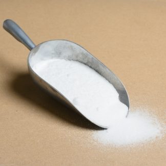 A spoon full of sugar on a brown surface.