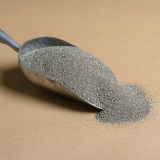 Sand in a metal scoop on a brown background.