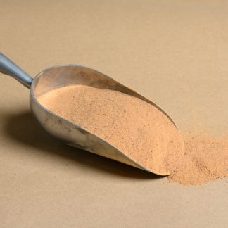 A scoop of brown powder on a beige background.