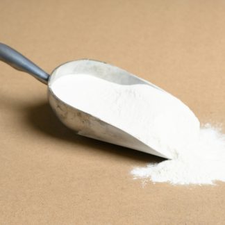A scoop of parlon white powder on a brown surface.